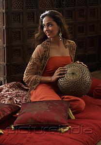 PictureIndia - Young woman sitting on pillows holding Indian antiques