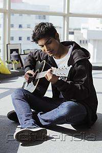 PictureIndia - young man sitting on floor playing guitar