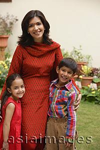 Asia Images Group - mother standing with son and daughter in garden, smiling at camera