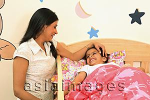 Asia Images Group - Mom tucking daughter into crib