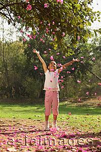 Asia Images Group - Little girl in park, tossing blossoms in air