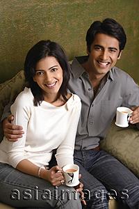 Asia Images Group - couple holding tea cups and smiling at camera