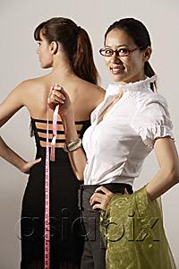 AsiaPix - Chinese fashion designer measuring model's dress, smiling at camera