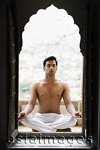 Asia Images Group - young man meditating in doorway