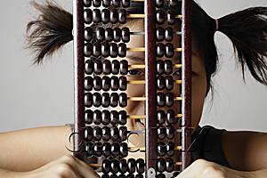 AsiaPix - Young woman peering through abacus.