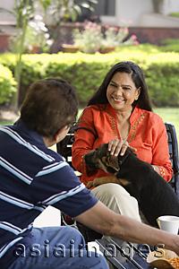 Asia Images Group - couple sitting outdoors, playing with dog