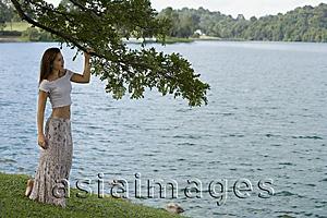 Asia Images Group - Woman standing under tree by lake