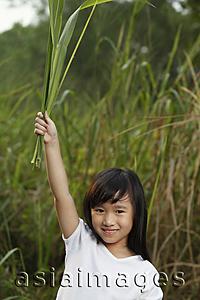 Asia Images Group - Girl holding leaves in air.