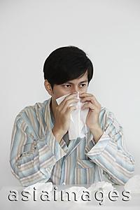 Asia Images Group - young man blowing his nose with tissue