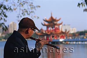 Asia Images Group - Taiwan,Kaohsiung,Man Playing Flute at Lotus Lake