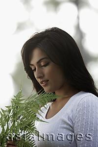 Asia Images Group - Back lit shot of young woman looking at a fern leaf