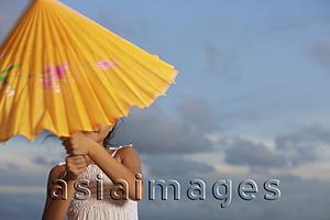 Asia Images Group - young girl trying to open up yellow umbrella