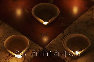 Asia Images Group - Lit clay oil lamps on floor