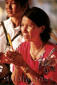Asia Images Group - Cambodia, Phnom Penh, Worshippers pray with incense at a temple.