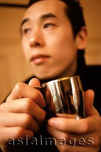 Asia Images Group - Man holding silver cup looking off camera.