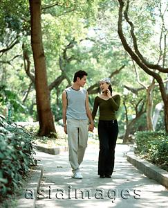 Asia Images Group - Young couple walking down path holding hands, nature in background.