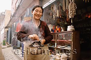 Asia Images Group - Nepal, Tibetan woman with juniper incense
