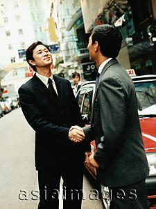 Asia Images Group - Executive pair shaking hands on street.