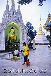 Asia Images Group - Myanmar (Burma), Yangon (Rangoon), Man sweeping tiles at Shwedagon Pagoda, man praying in background.