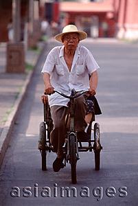 Asia Images Group - China, Beijing, man cycling, hat on head