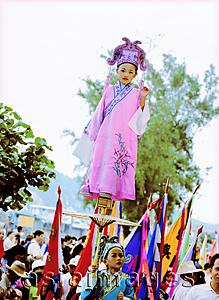 Asia Images Group - China, Hong Kong, Cheung Chau Island, Girl wearing a traditional costume, standing on tiny foothold held up by young boy during the Bun Festival procession in 2000