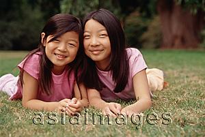 Asia Images Group - Two sisters lying on grass, cheek to cheek