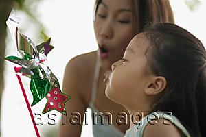 Asia Images Group - Young girl and mother blowing a pinwheel