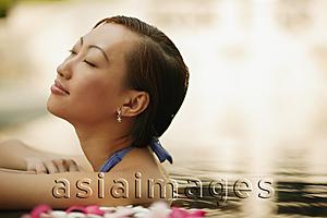 Asia Images Group - Young woman, at edge of swimming pool, head tilted up.