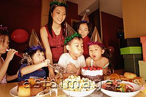 Asia Images Group - Young boy blowing out candles on a cake