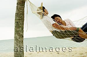 Asia Images Group - Couple lying in hammock on beach, sleeping