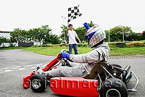 Asia Images Group - Young woman in go-cart, young man waving flag