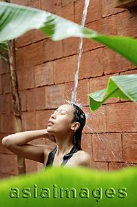 Asia Images Group - Woman taking outdoor shower, eyes closed