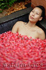Asia Images Group - Woman relaxing in tub with floating rose petals