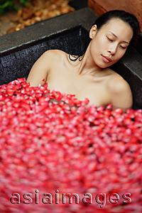 Asia Images Group - Woman relaxing in tub, eyes closed, petals floating around her