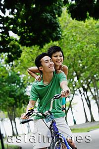 Asia Images Group - Young couple on tandem bicycle, smiling at camera