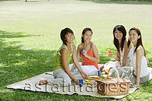 Asia Images Group - Young women sitting in park, having picnic, smiling at camera