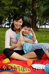 Asia Images Group - Mother and son on picnic blanket, smiling at camera