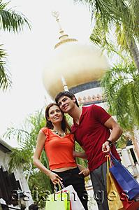 Asia Images Group - Couple standing side by side, mosque in the background