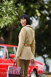 Asia Images Group - Woman with shopping bags, looking over shoulder