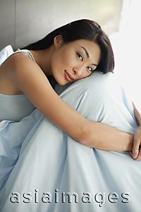 Asia Images Group - Woman hugging knees, smiling at camera