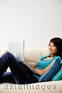 Asia Images Group - Woman on sofa, using laptop