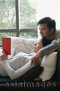 Asia Images Group - Couple in living room, reading a book together