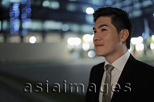 Asia Images Group - Profile of young man wearing a business suit at night.