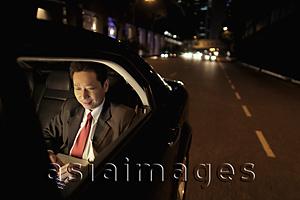 Asia Images Group - Mature man sitting in the back seat of a care working on a laptop