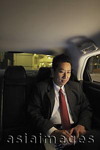 Asia Images Group - Mature man sitting in car working on laptop