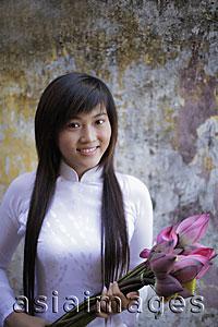 Asia Images Group - Young woman wearing traditional Vietnamese dress  holding lotus flowers