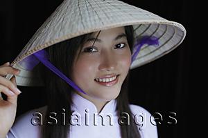 Asia Images Group - Young woman smiling, wearing Vietnamese hat