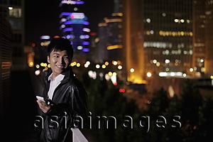 Asia Images Group - Young man holding a phone at night, Beijing, China