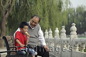 Asia Images Group - Grandfather with grandson in a park eating ice cream