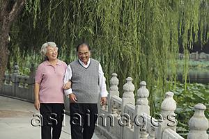 Asia Images Group - Older couple walking arm and arm in a park